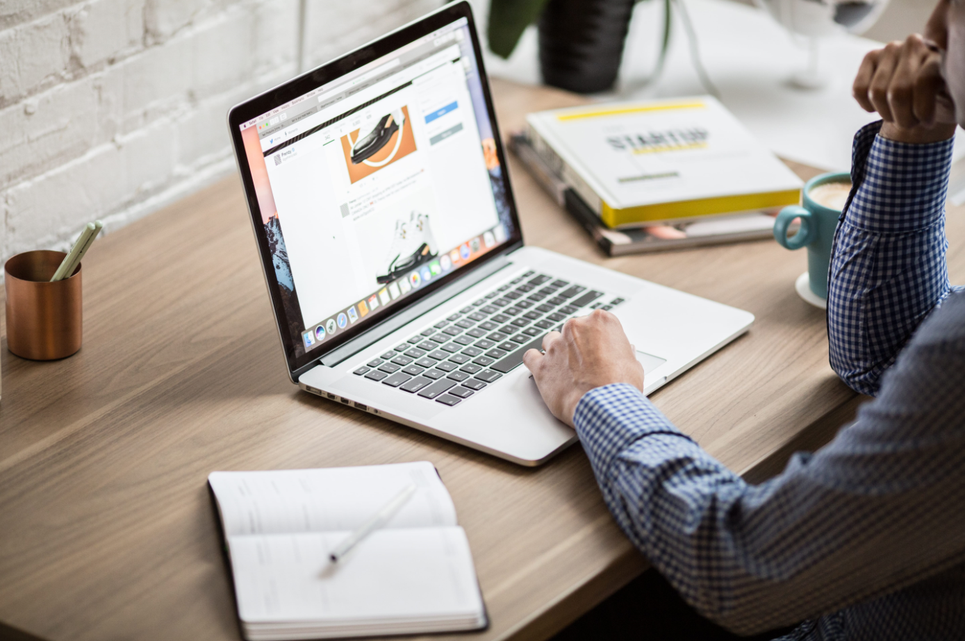 Mann sitzt am Tisch vor Laptop