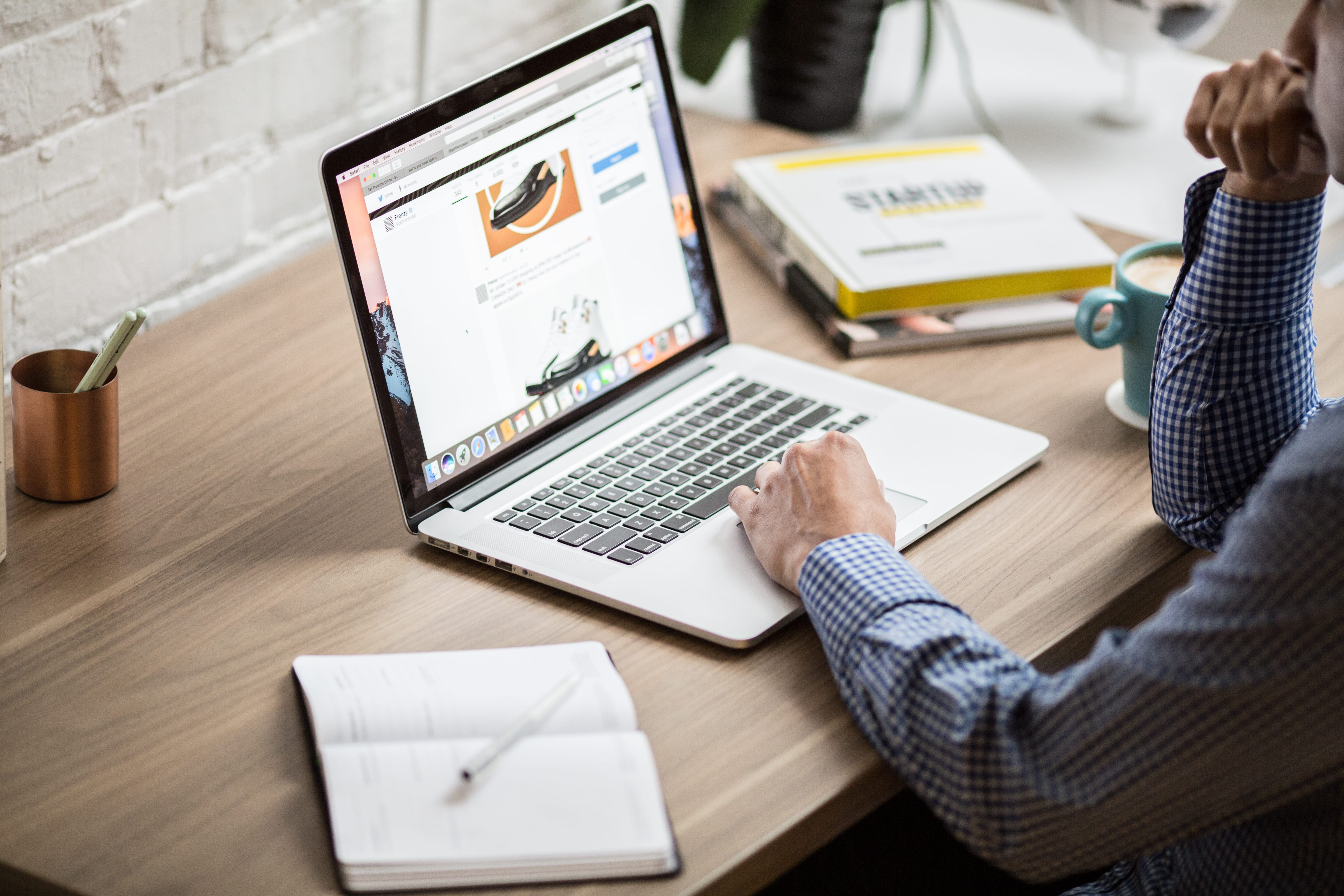 Mann sitzt am Tisch vor Laptop