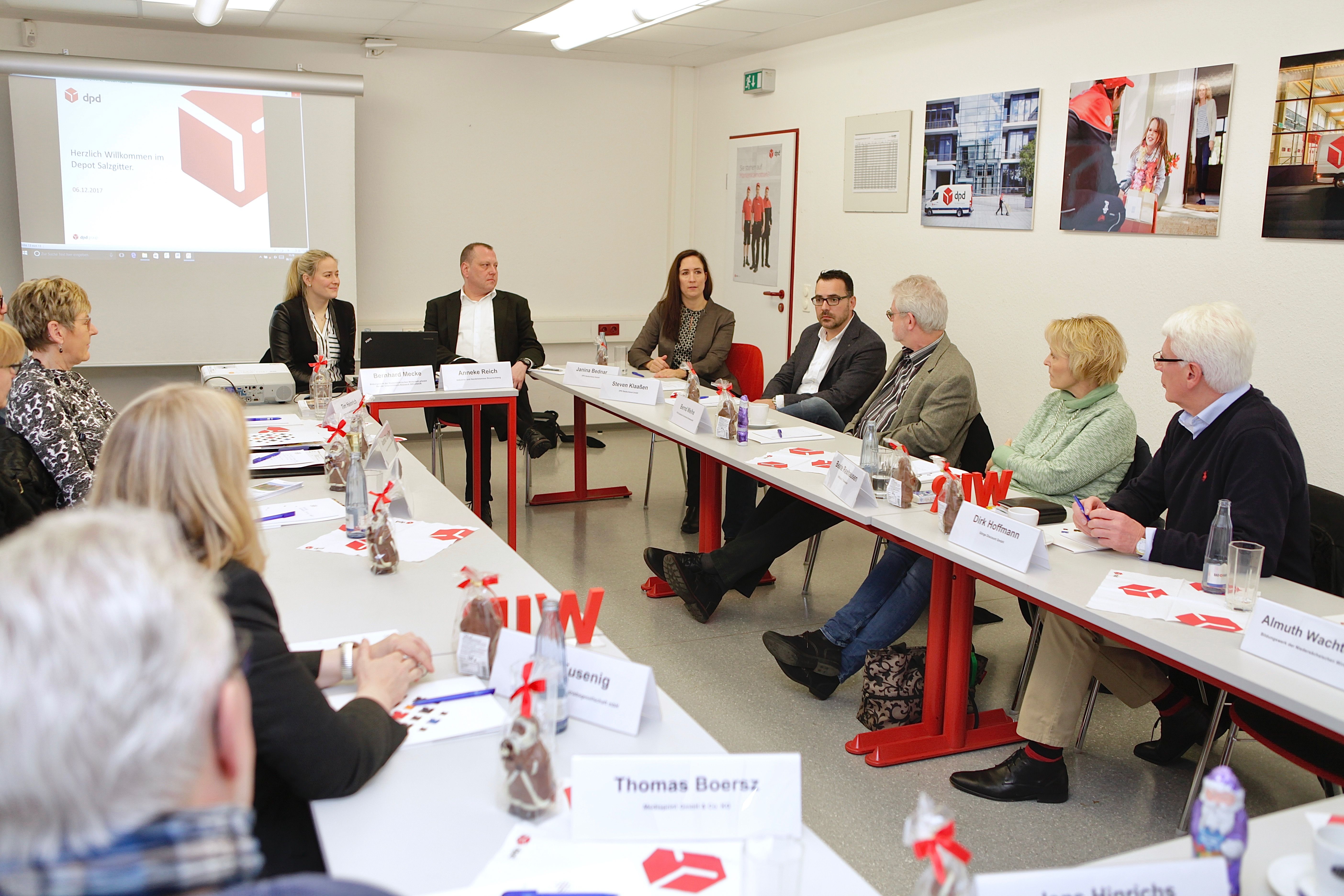 Menschen sitzen an Tischen in U-Form