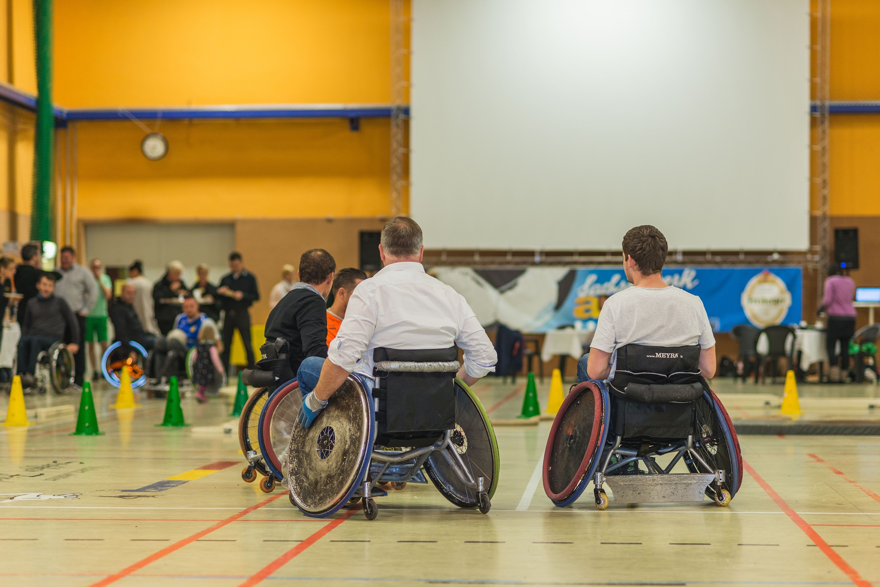 zwei Rollstuhlfahrer in einer Sporthalle