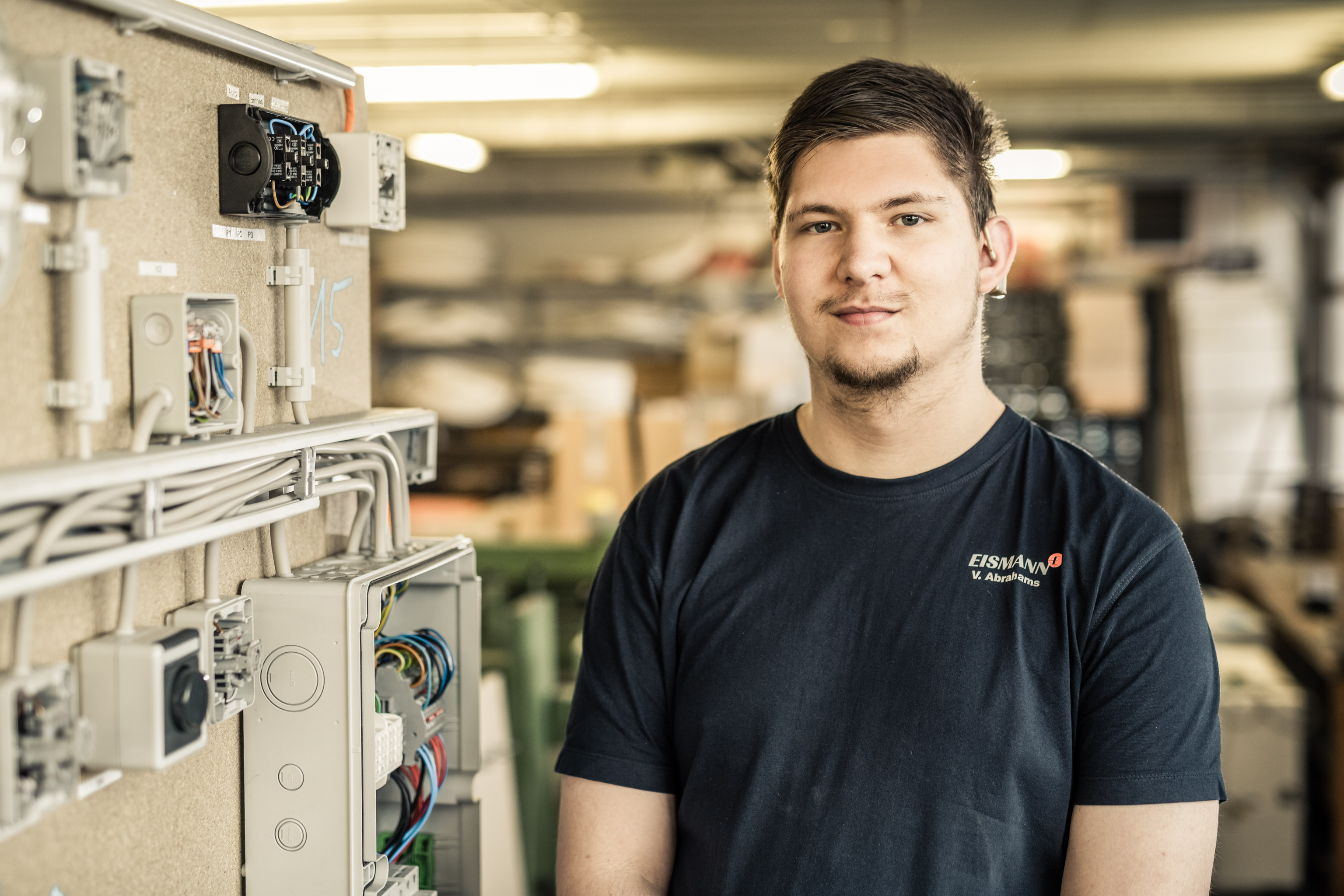 Junger Mann steht in Werkstatt neben Stromkasten