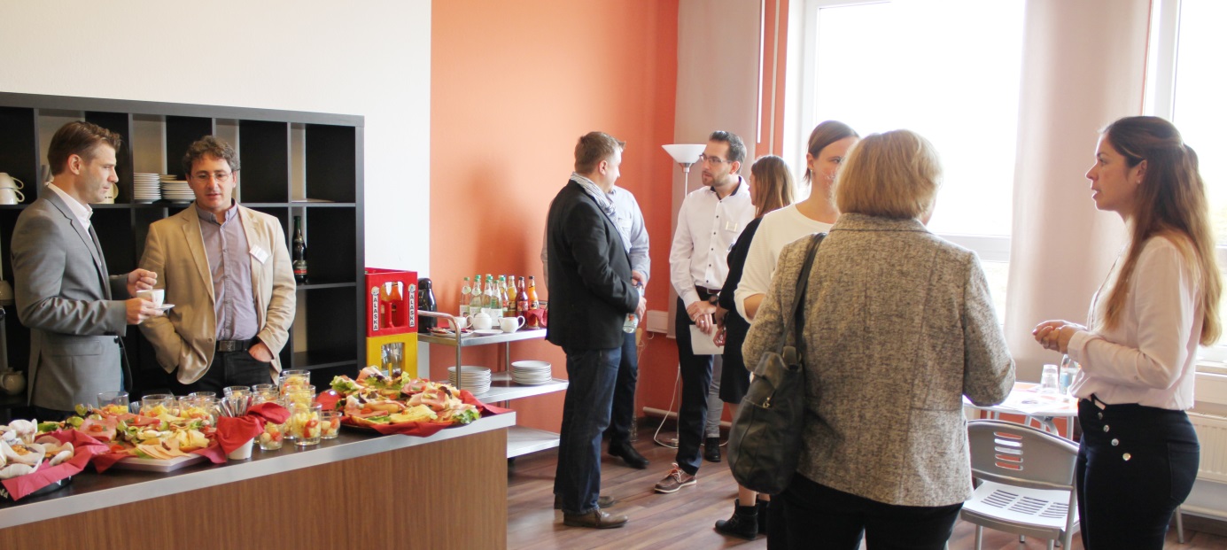 Menschen stehen in Raum in dem Frühstücksbuffet aufgebaut ist