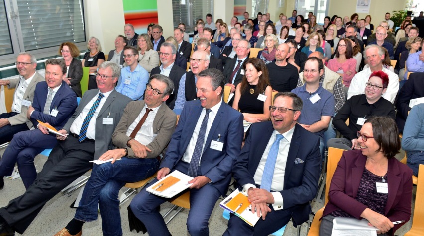 Menschen im Publikum gucken nach vorn und lachen.