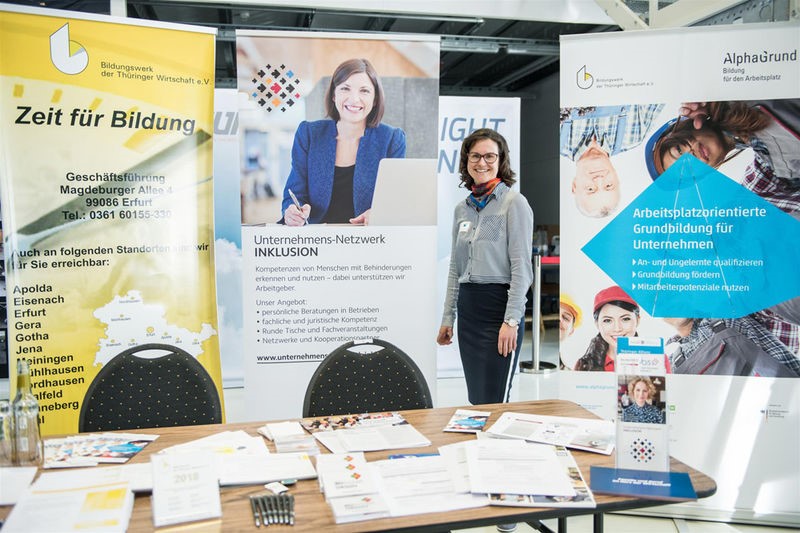 Frau steht am Messe-Infostand